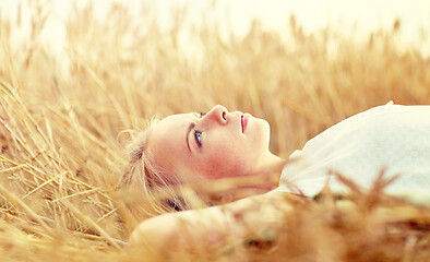 Image showing young woman lying on cereal field and dreaming