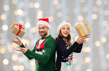 Image showing happy couple in christmas sweaters with gifts