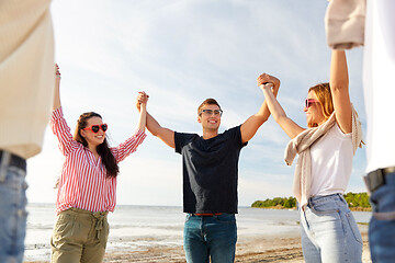 Image showing happy friends holding hands on summer beach