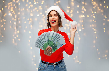 Image showing happy woman in santa hat with money on christmas