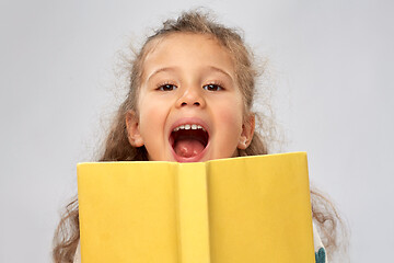 Image showing happy little girl hiding behind yellow book