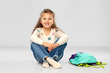 Image showing happy little girl with school bag sitting on floor