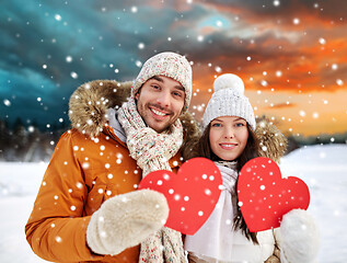 Image showing happy couple with red hearts over winter landscape