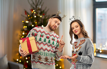 Image showing happy couple in christmas sweaters with gift box