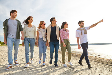 Image showing happy friends walking along summer beach