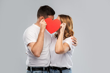 Image showing smiling couple kissing behind big red heart