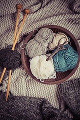 Image showing Home life - Knitting concept, knitting needles with blanket, scissors and yarn in wooden bowl