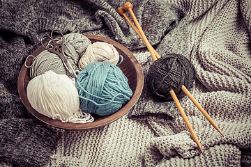 Image showing Home life - Knitting concept, knitting needles with blanket, scissors and yarn in wooden bowl