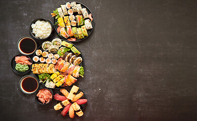 Image showing Assorted sushi set served on dark dark background. Top view of seafood, various maki rolls