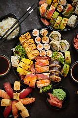 Image showing Assorted sushi set served on dark dark background. Top view of seafood, various maki rolls