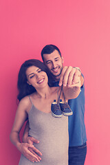 Image showing young pregnant couple holding newborn baby shoes