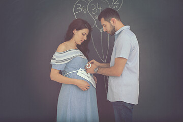 Image showing pregnant couple drawing their imaginations on chalk board