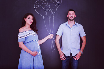 Image showing pregnant couple drawing their imaginations on chalk board