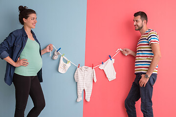 Image showing young couple holding baby bodysuits