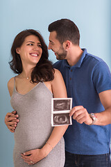 Image showing couple looking ultrasound picture isolated on blue background