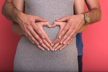 Image showing pregnant  couple showing heart with their hands