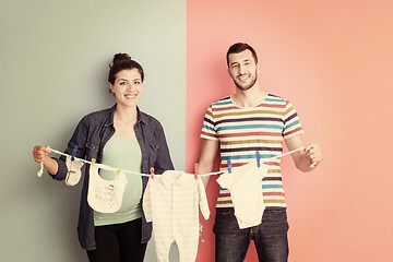 Image showing young couple holding baby bodysuits