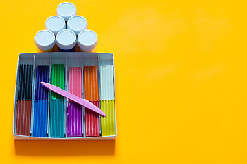 Image showing There are jars of gouache above the plasticine box, yellow background