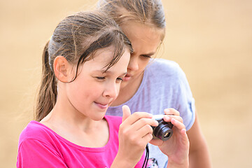 Image showing Two girls watching photos on the screen of a digital camera