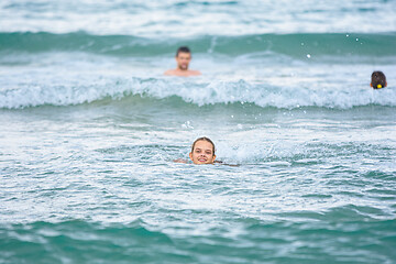 Image showing A girl swims in the sea, several more people are swimming in the background