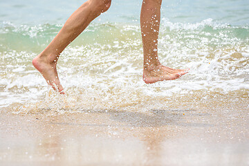 Image showing Funny feet running along the beach splashing sea water