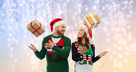 Image showing happy couple in christmas sweaters with gifts