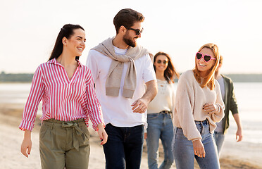 Image showing happy friends walking along summer beach