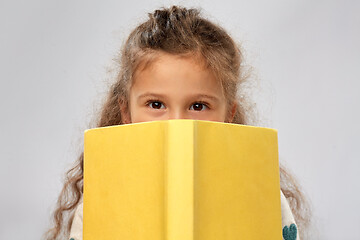 Image showing little girl hiding behind yellow book