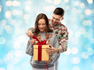 Image showing happy couple in christmas sweaters with gift box