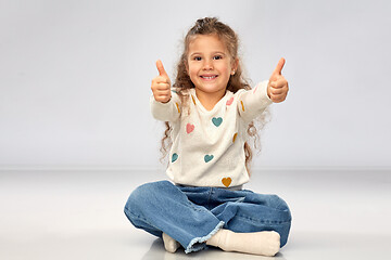 Image showing little girl sitting on floor and showing thumbs up