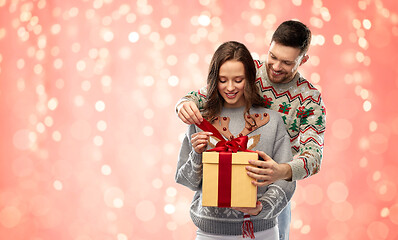 Image showing happy couple in christmas sweaters with gift box