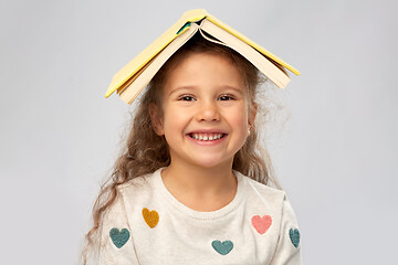 Image showing portrait of smiling girl with book on head