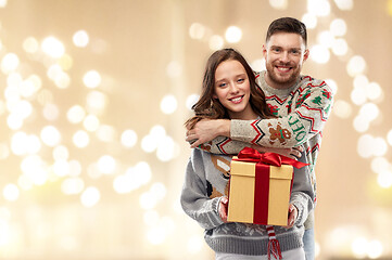 Image showing happy couple in christmas sweaters with gift box