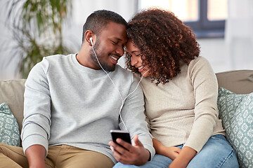 Image showing happy couple with smartphone and earphones at home