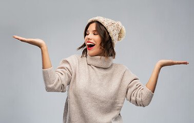 Image showing young woman in winter hat holding something