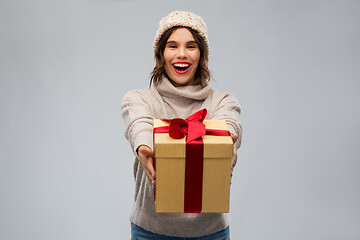 Image showing young woman in knitted winter hat holding gift box