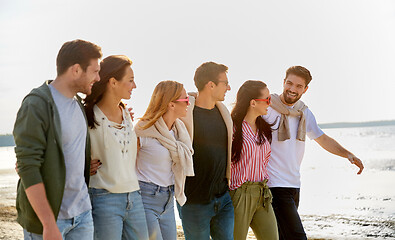 Image showing happy friends walking along summer beach