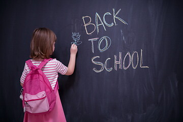 Image showing school girl child with backpack writing  chalkboard