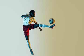 Image showing Male soccer player kicking ball in jump isolated on gradient background
