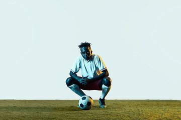 Image showing Male soccer player sitting with the ball isolated on white background