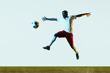 Image showing Male soccer player kicking ball isolated on white background