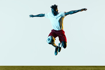 Image showing Male soccer player kicking ball isolated on white background