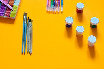 Image showing Stationery, plasticine, brushes, gouache and felt-tip pens lie on an orange background