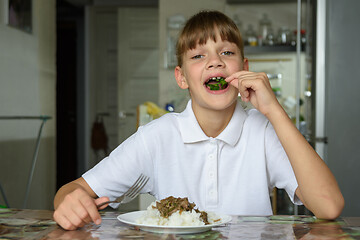 Image showing Happy little girl happily eating fresh herbs at lunch