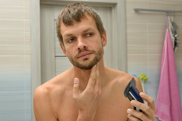 Image showing The man has trimmed his beard and looks in the mirror the result