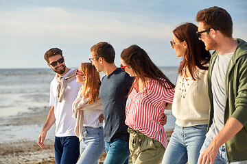 Image showing happy friends walking along summer beach