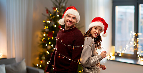 Image showing couple in santa hats tied by christmas garland