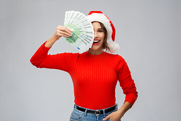 Image showing happy woman in santa hat with money on christmas