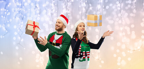 Image showing happy couple in christmas sweaters with gifts