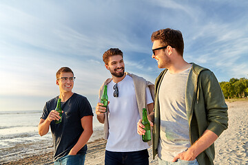 Image showing young men with non alcoholic beer walking on beach